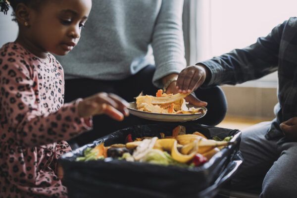 A family making biodegradable compost from vegetable and fruit leftovers as an effort to reduce food waste at home.