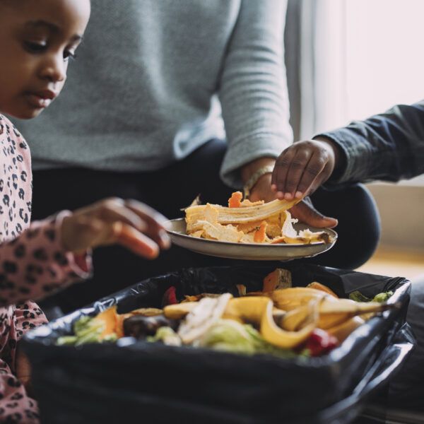 A family making biodegradable compost from vegetable and fruit leftovers as an effort to reduce food waste at home.